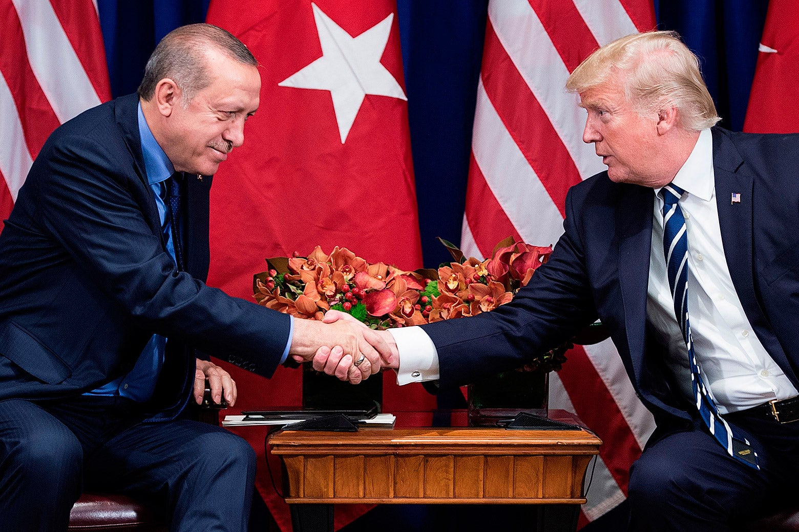 Recep Tayyip Erdogan and Donald Trump, seated, shake hands.