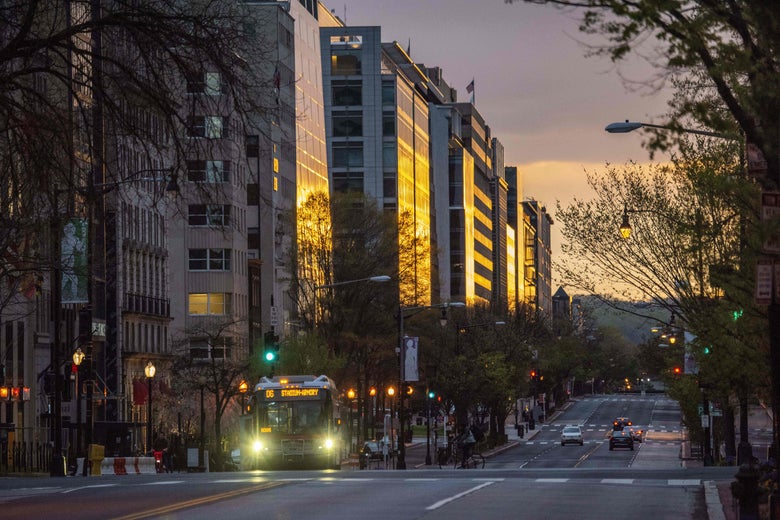 A bus on an almost empty street in downtown Washington as the sun sets.
