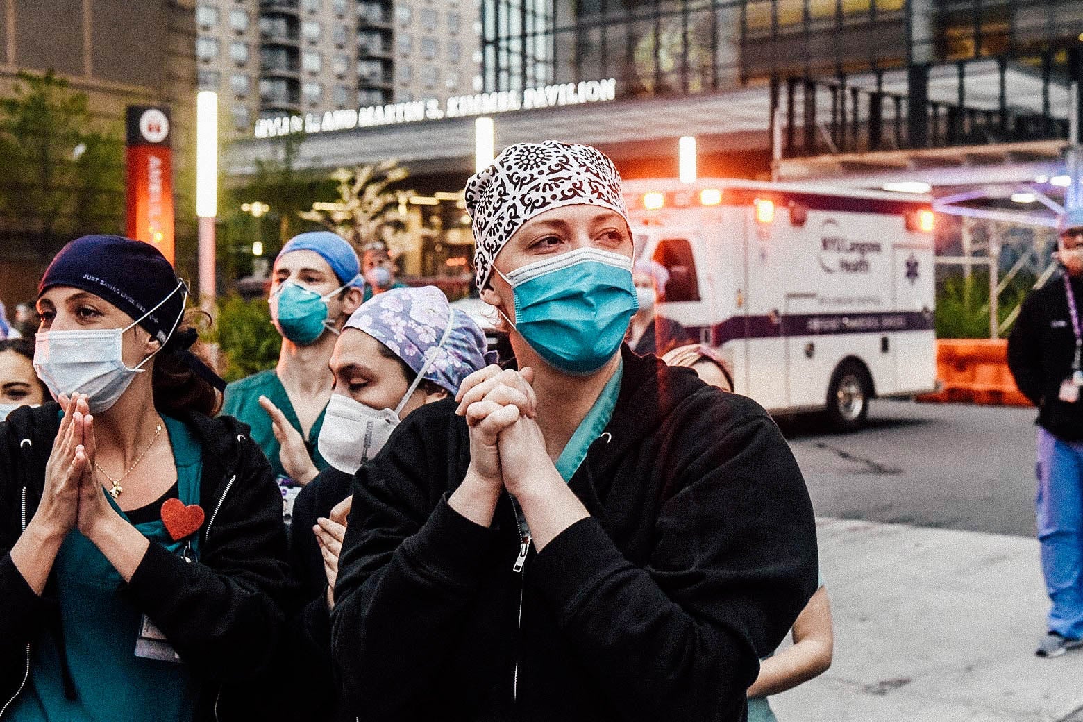 Nurses in masks stand outside a hospital.