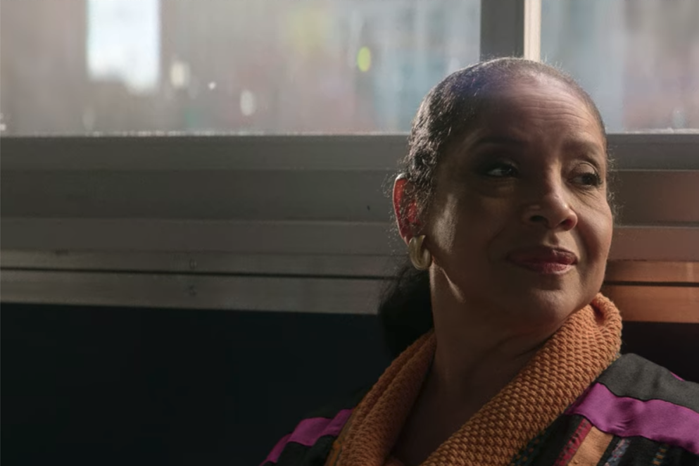 Phylicia Rashad sits with her back to a diner window.