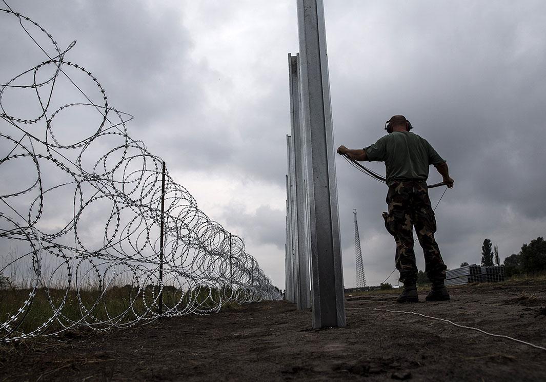 A member of the Hungarian Defence Force installs barbed wire on the Hungarian-Serbian border to prevent refugees from entering Hungary on Aug. 17, 2015