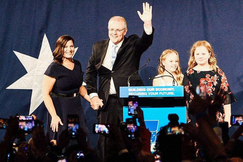 Scott Morrison waves to the crowd as he holds his wife's hand.