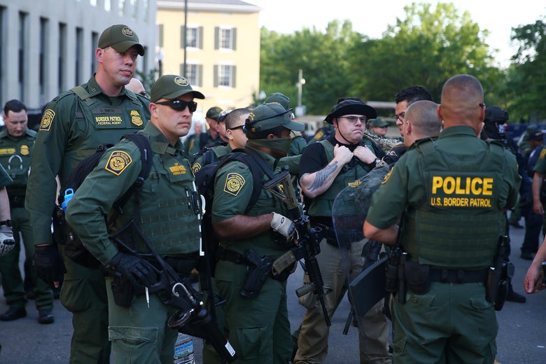 Border Patrol members, wearing gear, gather in a group.