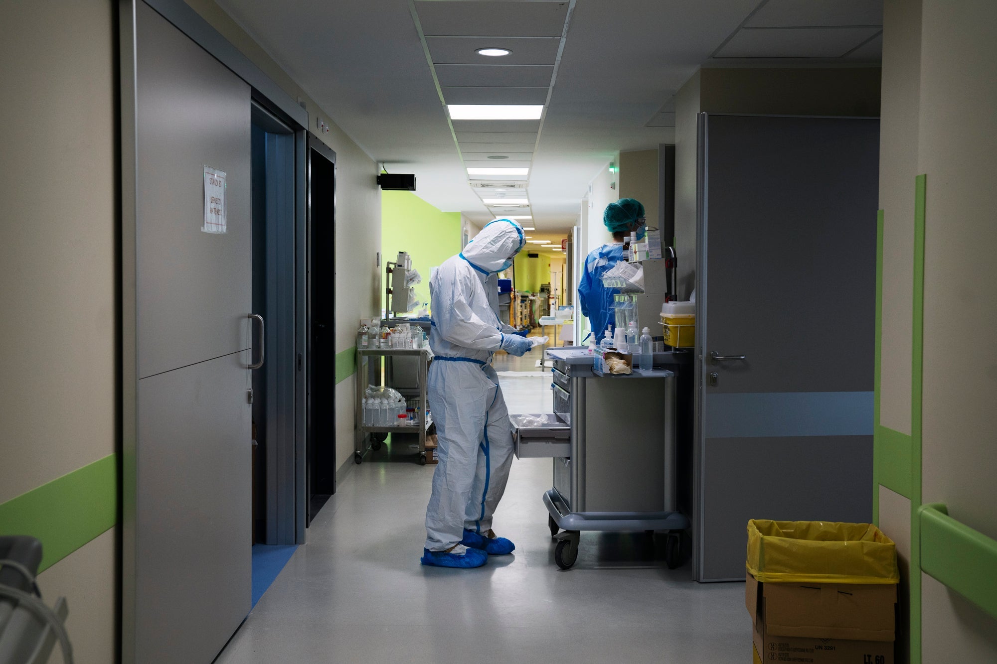 Medical workers in PPE in a hospital hallway.