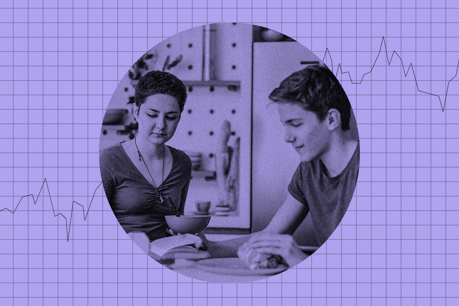 Two teenagers at a kitchen table looking at a book.