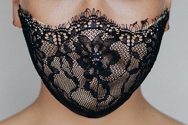The bottom half of a woman's face wearing a black lace mask that covers her mouth and nose.