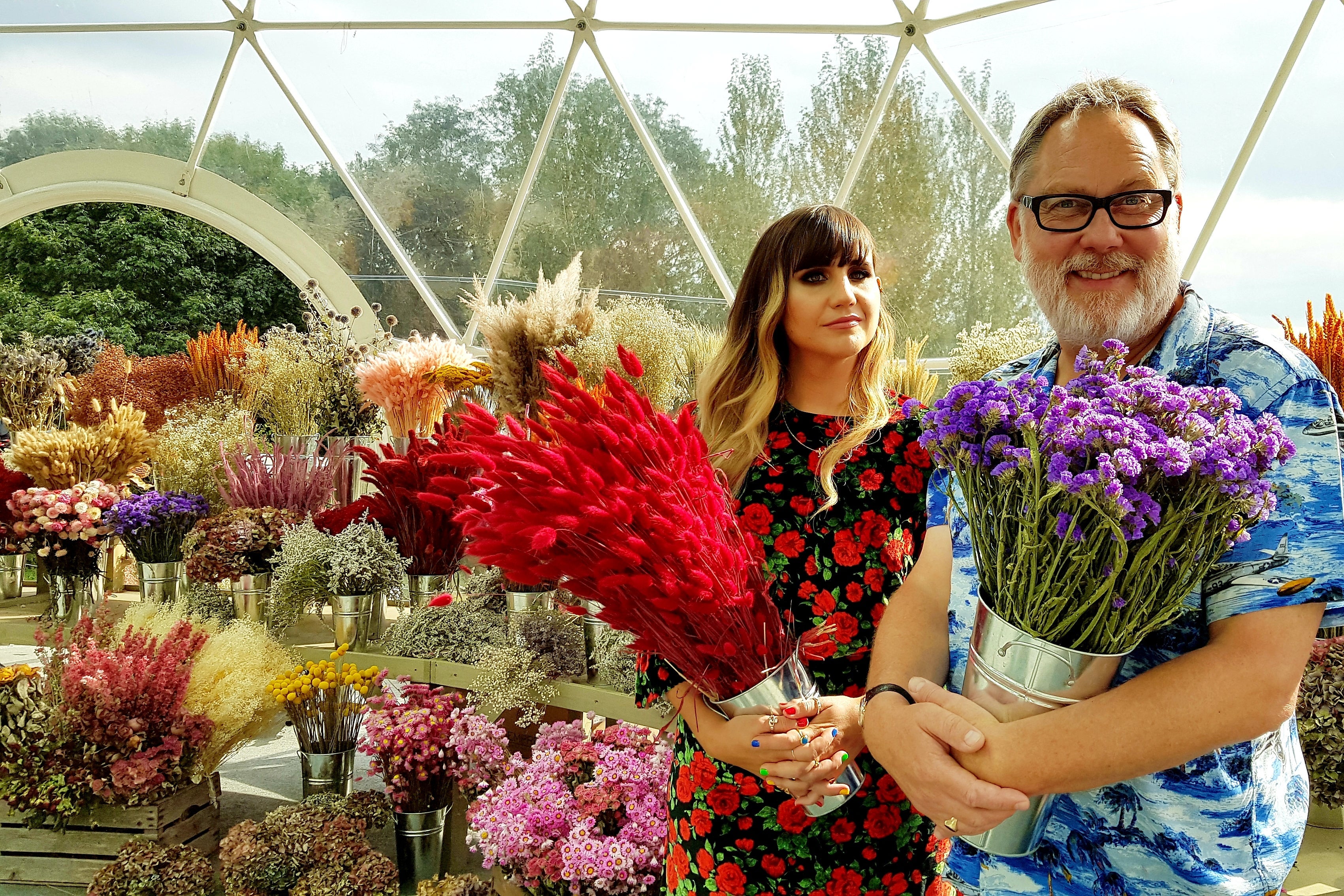 The hosts of The Big Flower Fight, surrounded by flowers.