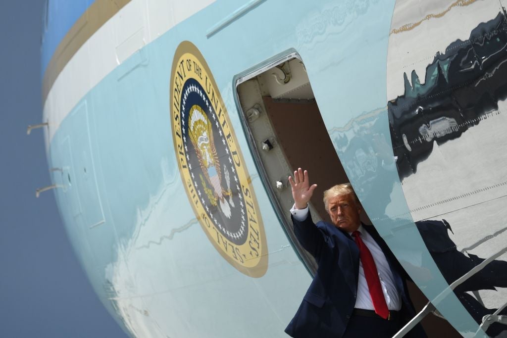 Trump waves from the top of a staircase as he boards Air Force One.