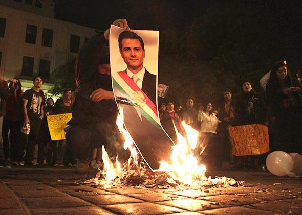 A demonstrator burns a photograph of Mexico's President Enrique Pena Nieto during a protest in support of the 43 missing Ayotzinapa students, in Monterrey November 20, 2014.