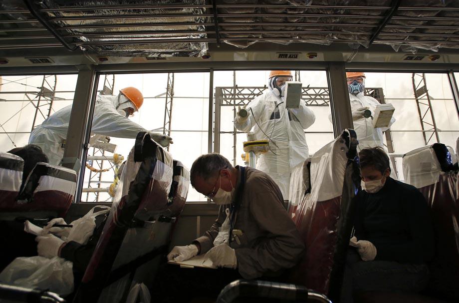Workers carry out radiation screening on a bus for a media tour at Tokyo Electric Power Co. (TEPCO)'s tsunami-crippled Fukushima Dai-ichi nuclear power plant.