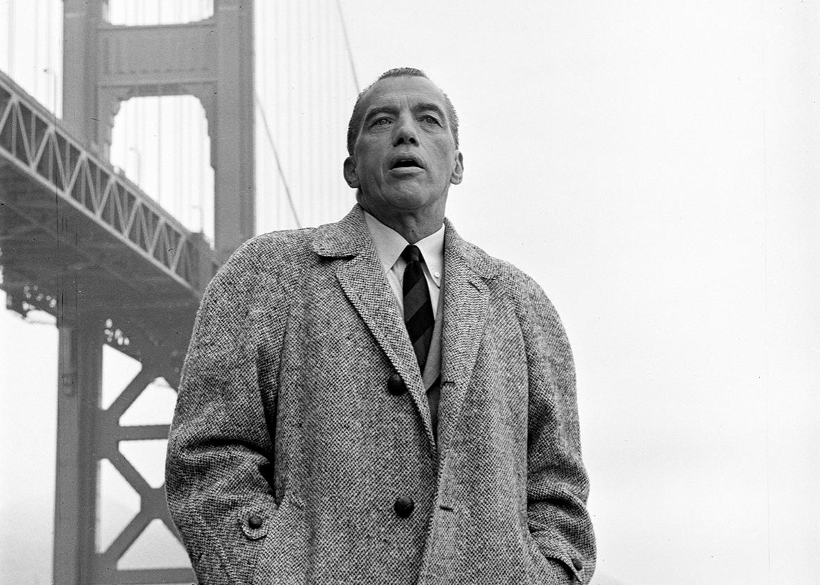 American television personality Ed Sullivan, dressed in an overcoat, stands in front of the Golden Gate Bridge during the filming of an episode of his tv show, San Francisco, California, September 17, 1960.