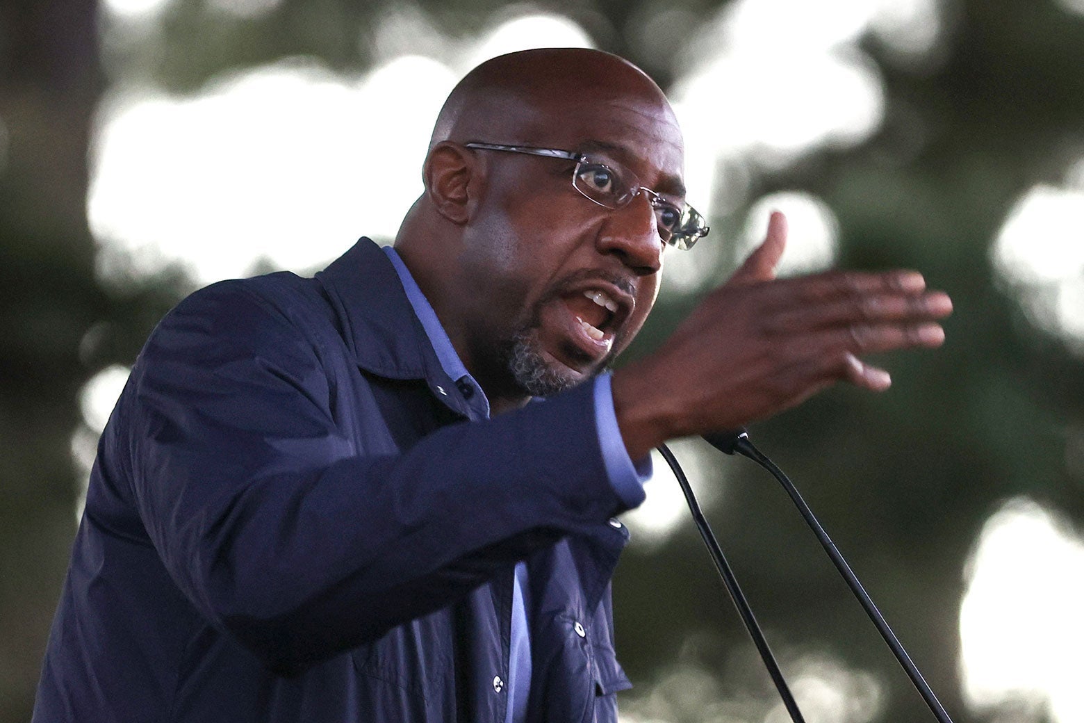 Raphael Warnock gestures while speaking into a microphone.