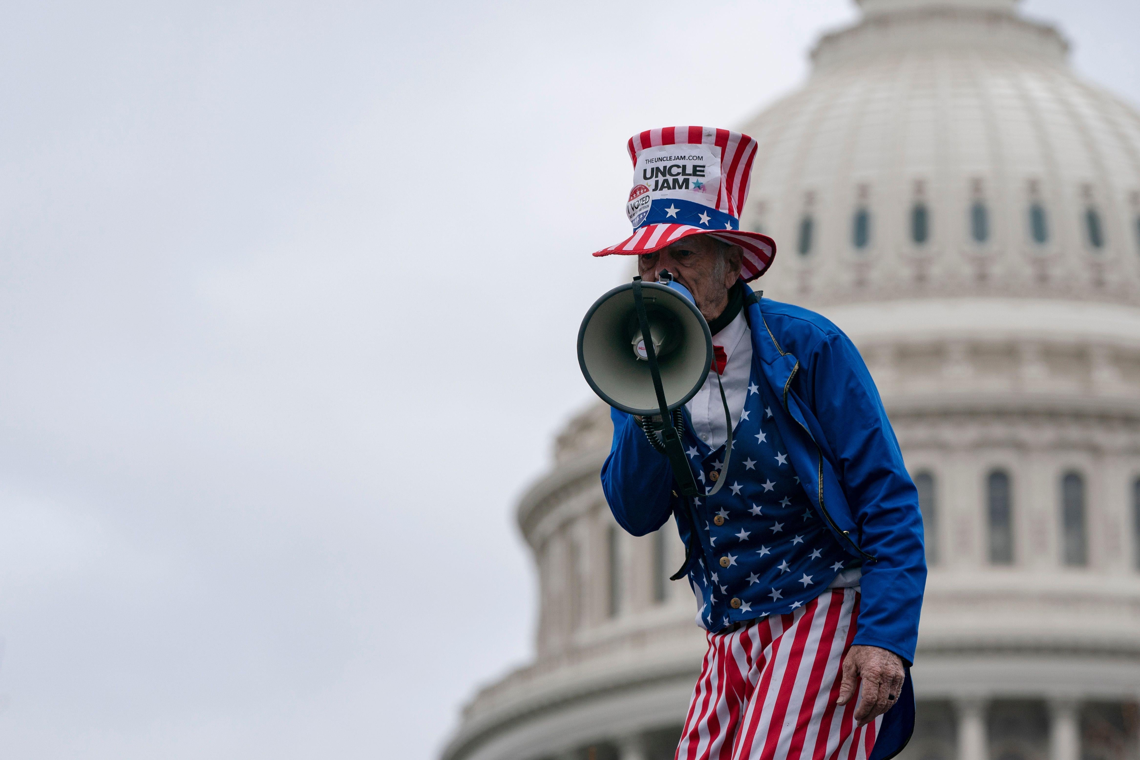 A man in an Uncle Sam costume speaks into a megaphone outside the U.S. Capitol.