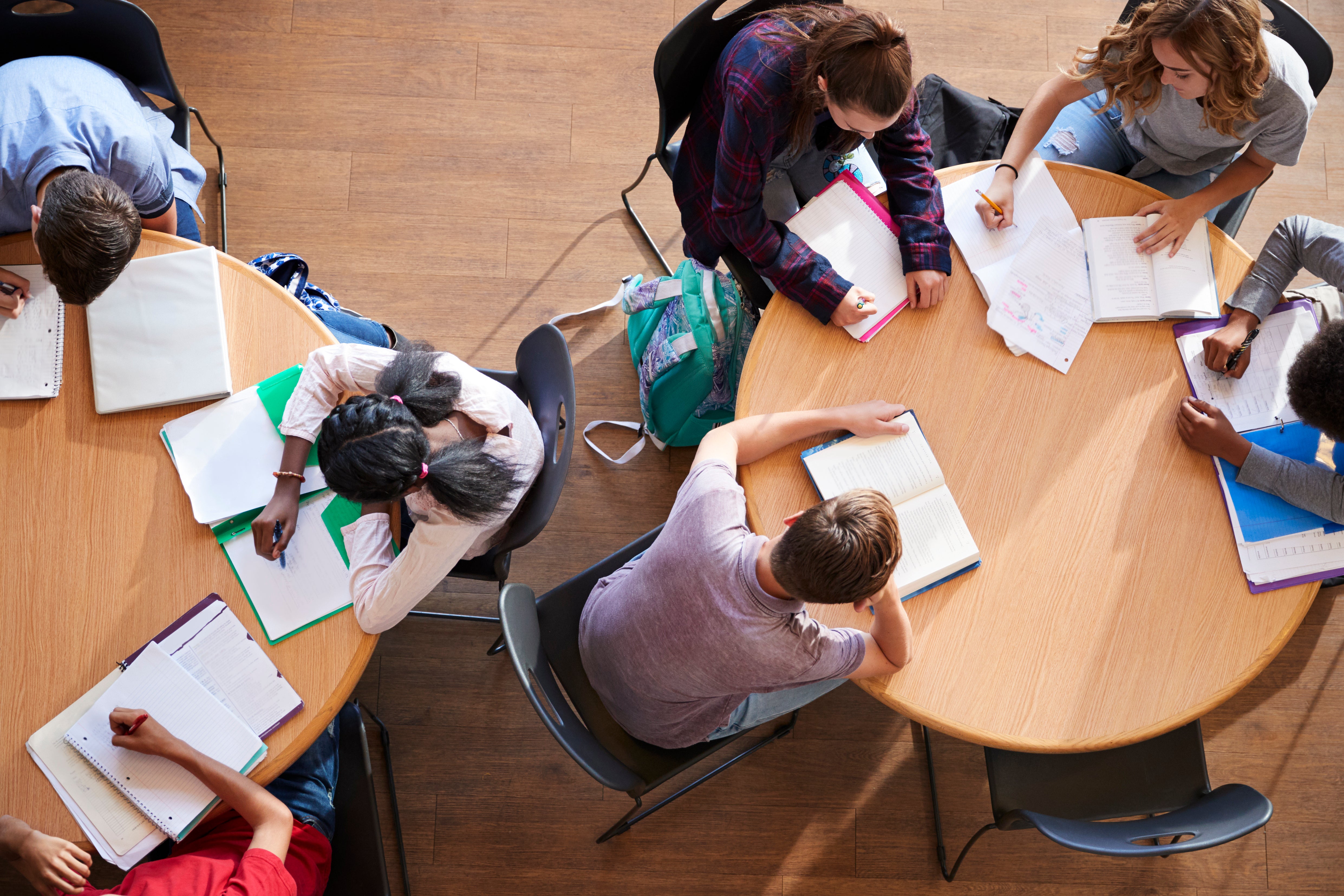 College-age students sitting around a table, working in notebooks and otherwise not using A.I.