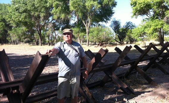 Glenn Spencer stands near a five foot "Normandy-style" fence near his property, on the US-Mexico border.