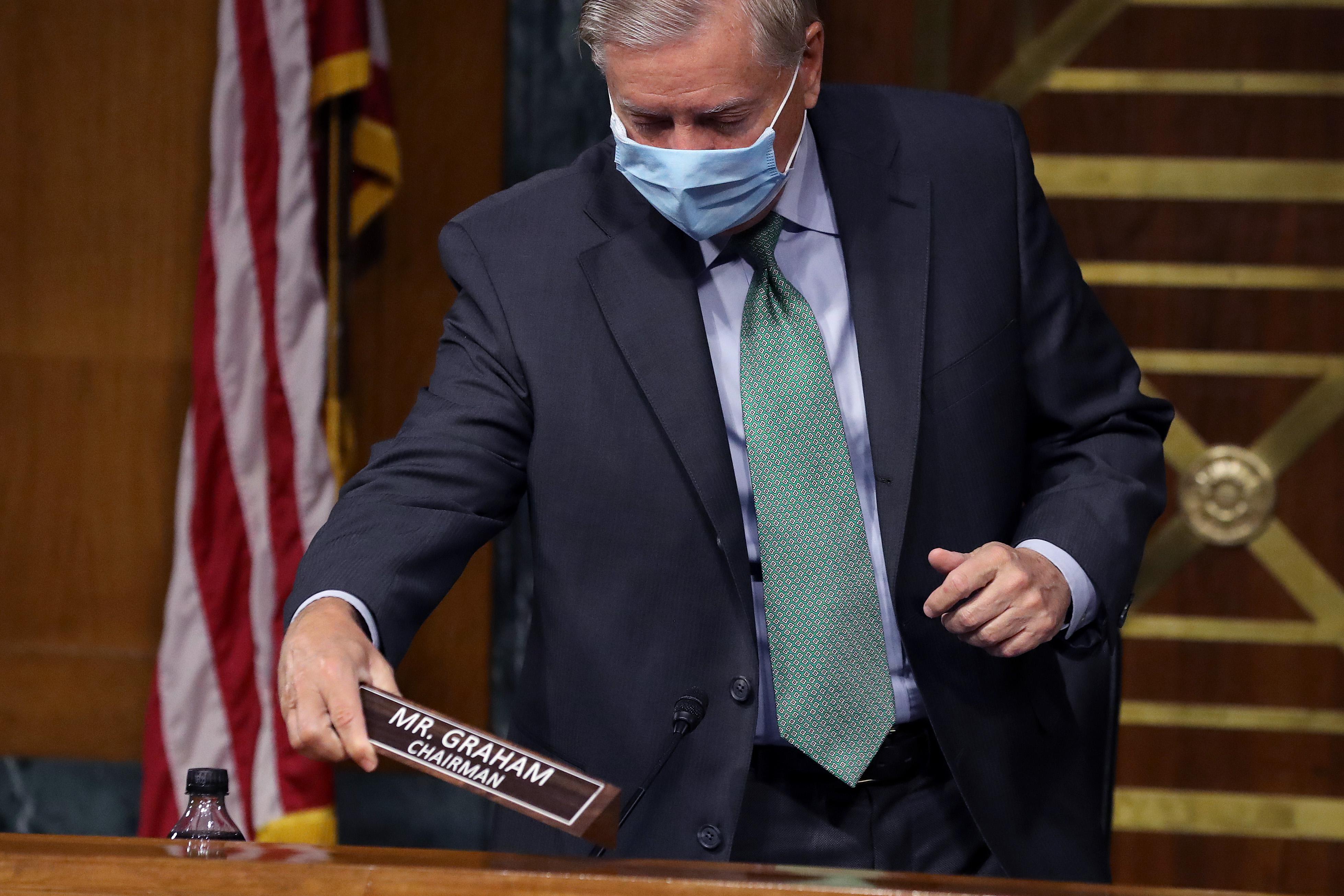 Graham holds his name plaque as he stands over his place on the judiciary committee's dais.