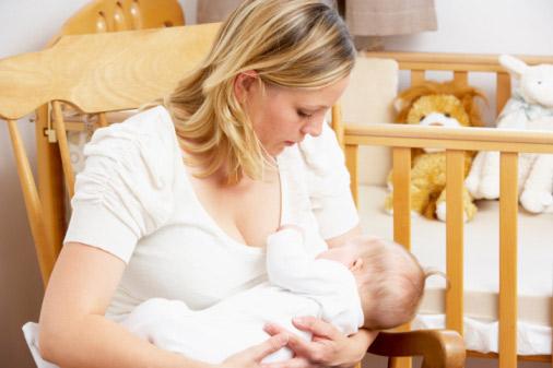 Mother breastfeeding baby in nursery.