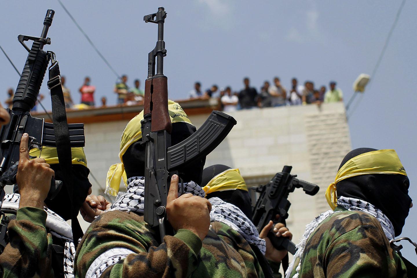 Fatah movement members holding their arms during the funeral of Mahmud Shawamreh.