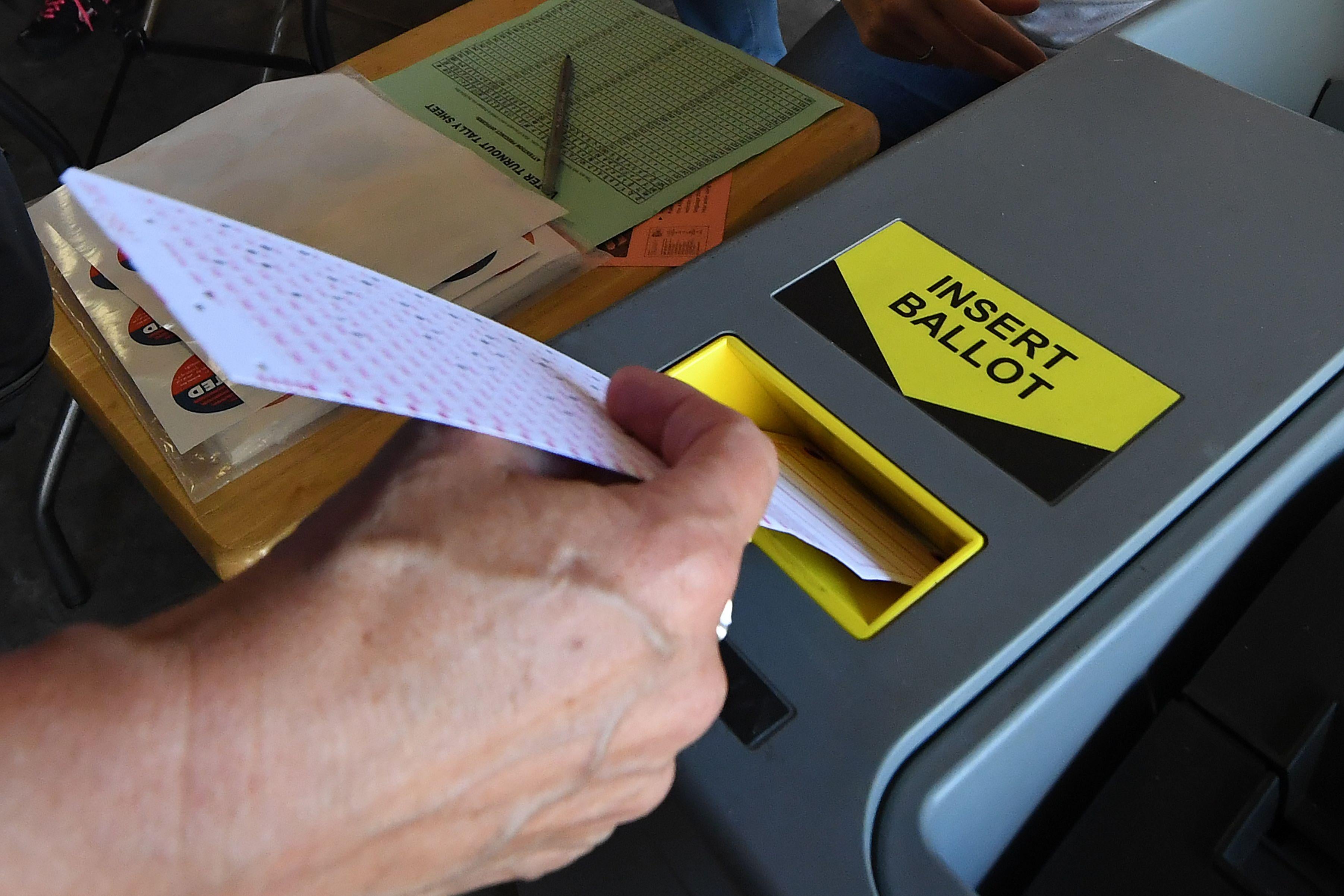 A woman inserts her ballot into the machine.