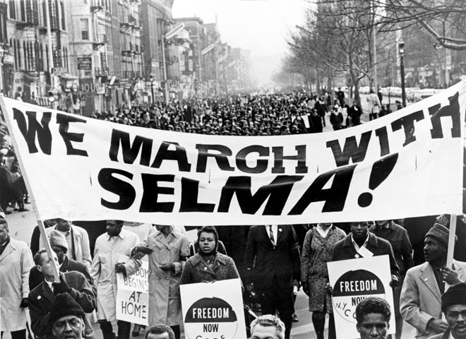 Marchers carry a “We march with Selma!” banner on a street in Harlem in New York City