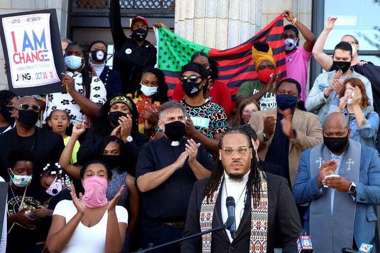 A group of protesters, including Gregory Drumwright at the mic, stand on the courthouse steps, cheering and holding up racial justice signs