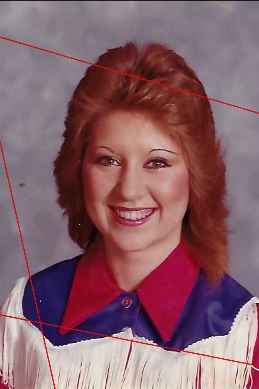 A woman with teased reddish hair in an ’80s-style fringe neon-pink top.