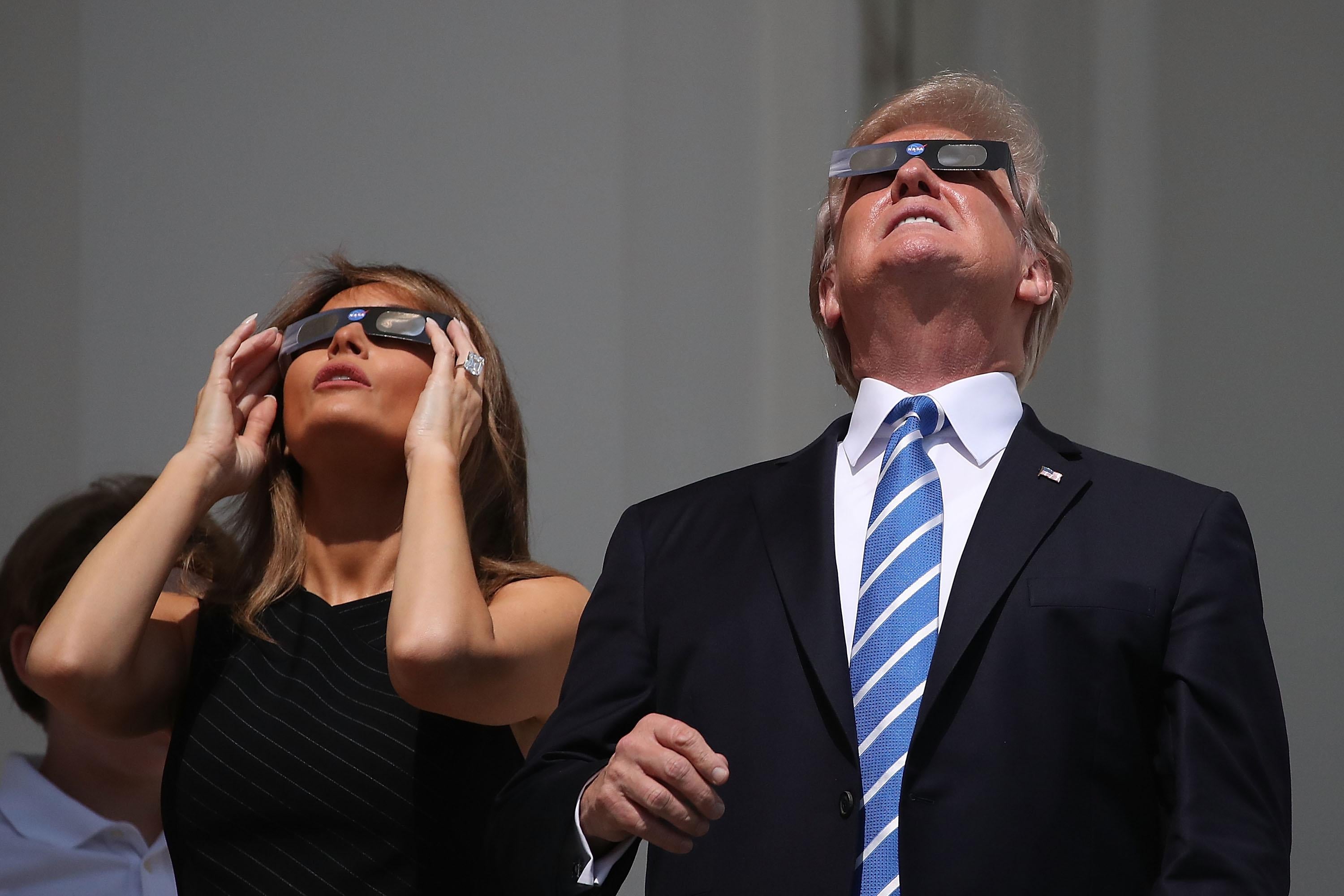 Donald and Melania Trump squint up at the sun through special eclipse glasses.