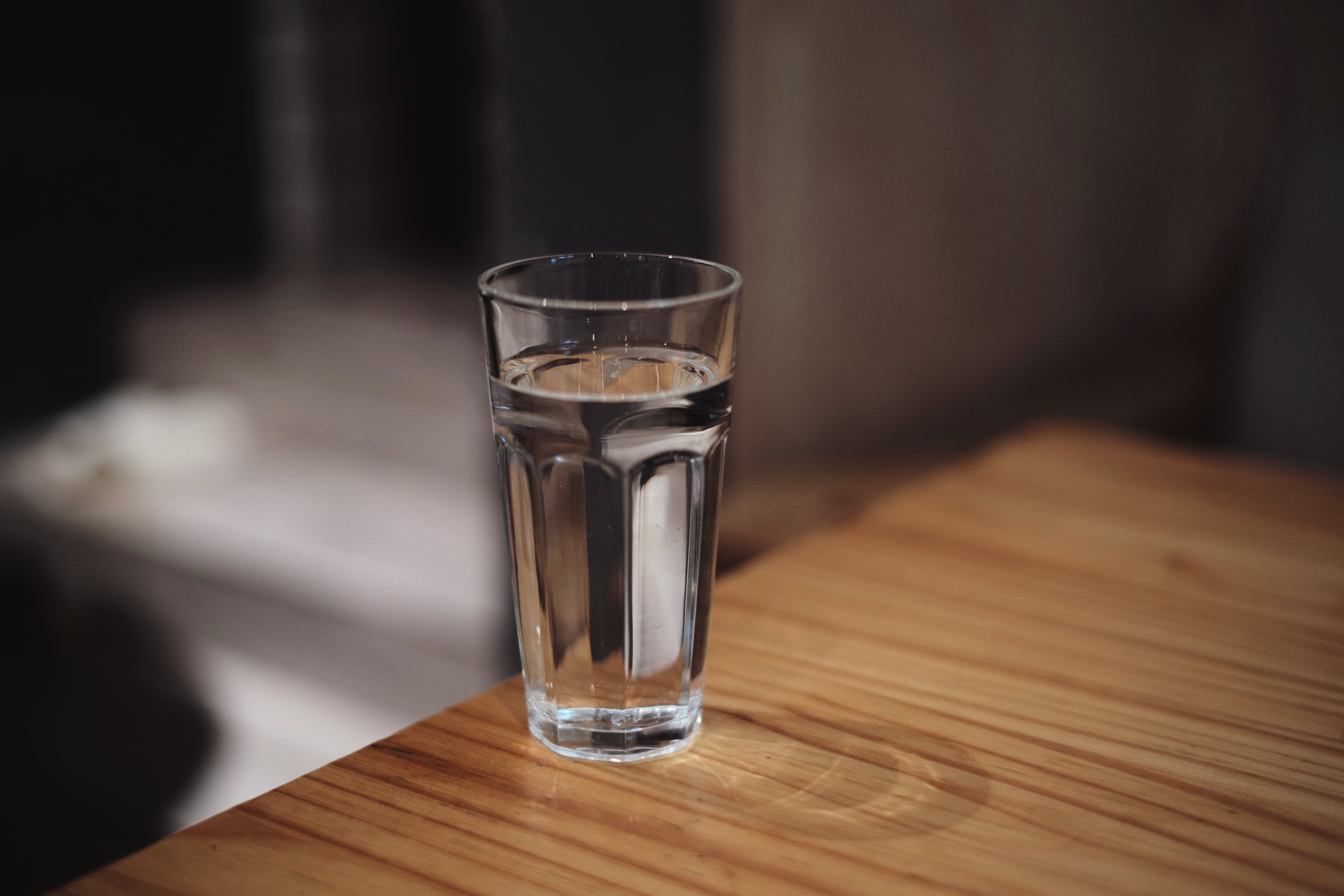 A glass of water on the edge of a table.