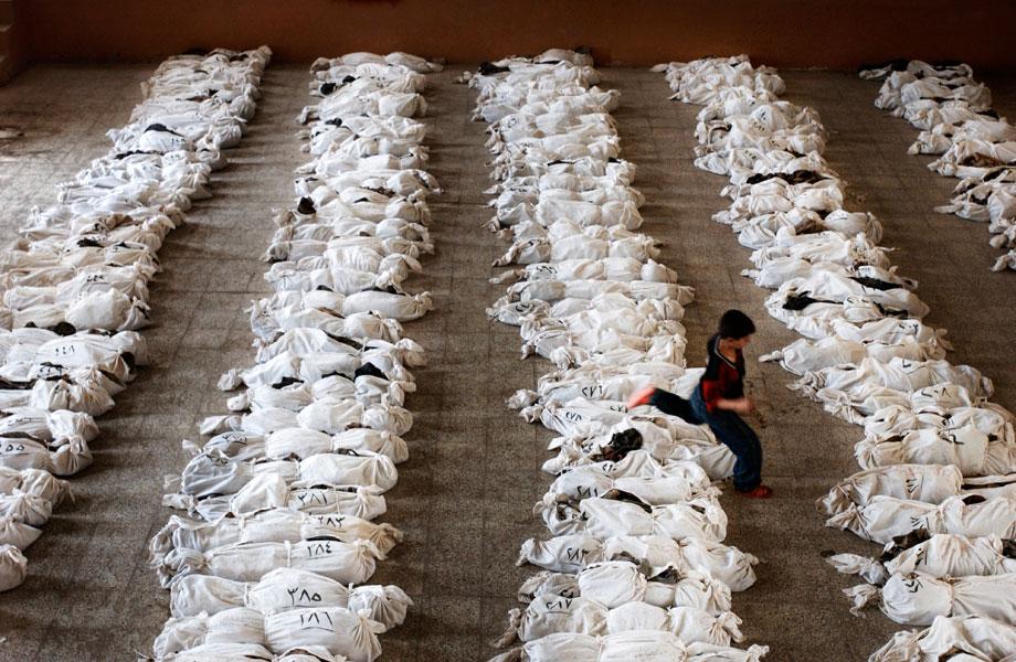 AL MUSAYYIB, Iraq—An Iraqi child jumps over the remains of victims found in a mass grave south of Baghdad. The bodies had been brought to this school for identification by family members who searched for identity cards and other clues among the skeletons to identify missing family members. The victims were killed by Saddam Hussein’s government following a Shi’ite uprising here after the 1991 Gulf War, May 27, 2003.