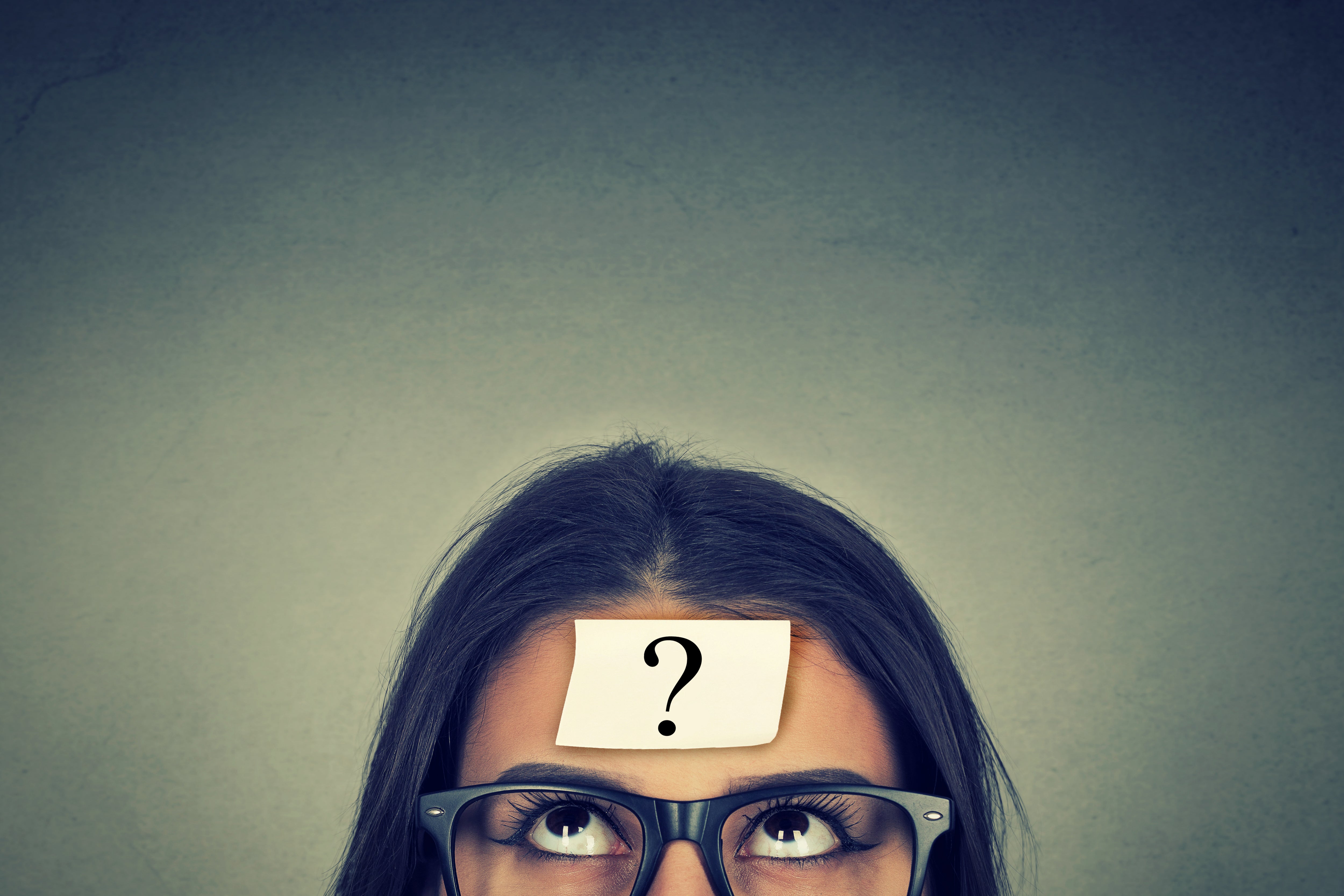 Woman in glasses with a question mark on her forehead.