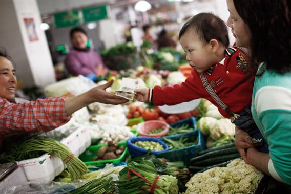 A woman asks her child to pay for vegetables at a food market in Shanghai, China on March 9, 2013.