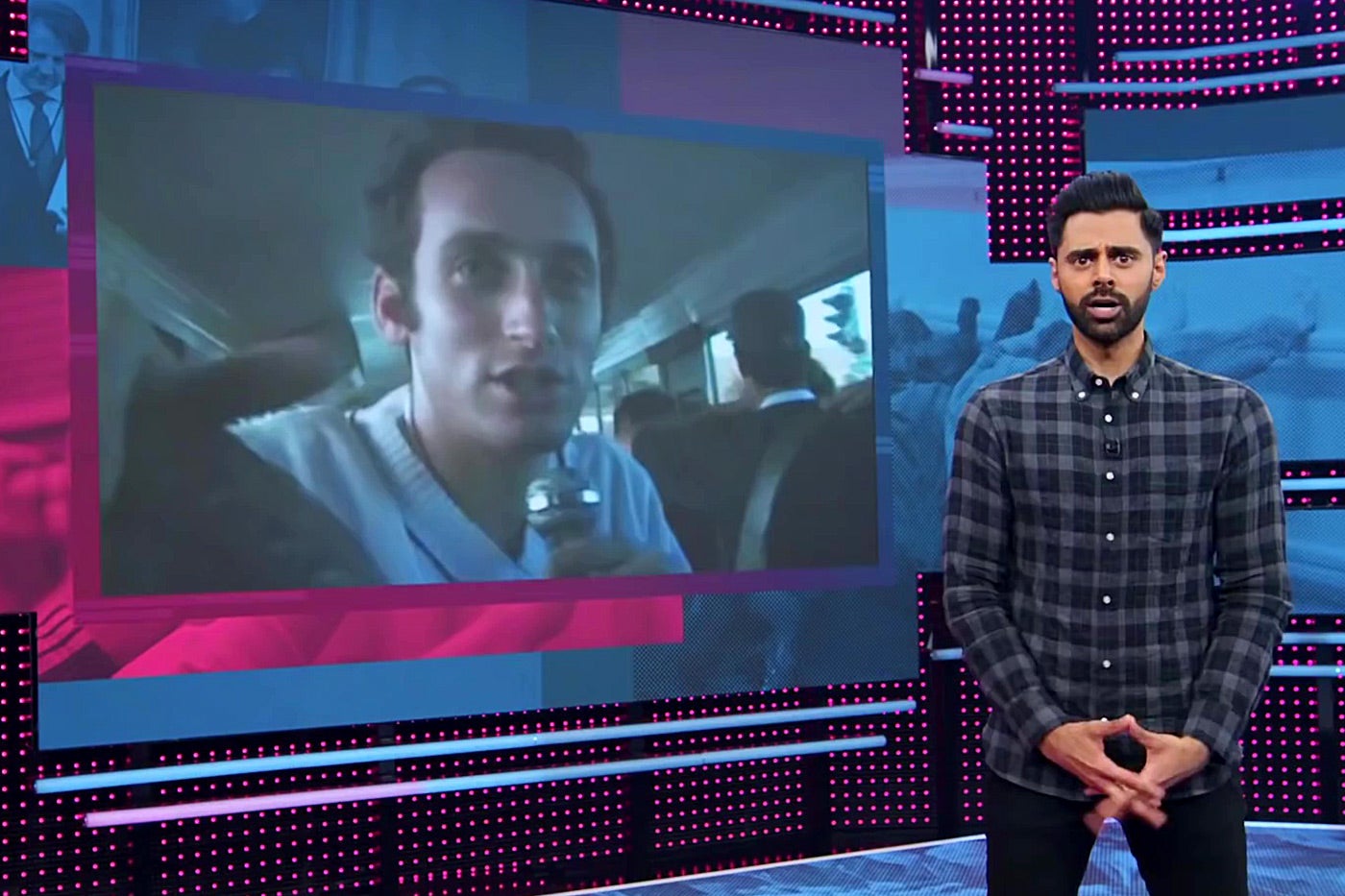 Hasan Minhaj in front of a photo of young Stephen Miller.