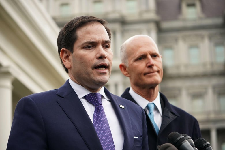 Marco Rubio speaks to reporters while Rick Scott stands by.