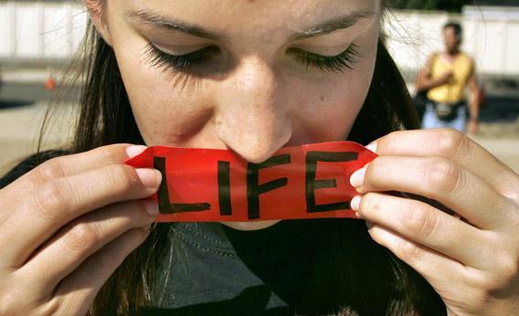 Abigail Brown of Phoenix, Arizona, puts a 'LIFE' sticker over her mouth while praying in front of the Supreme Court building/