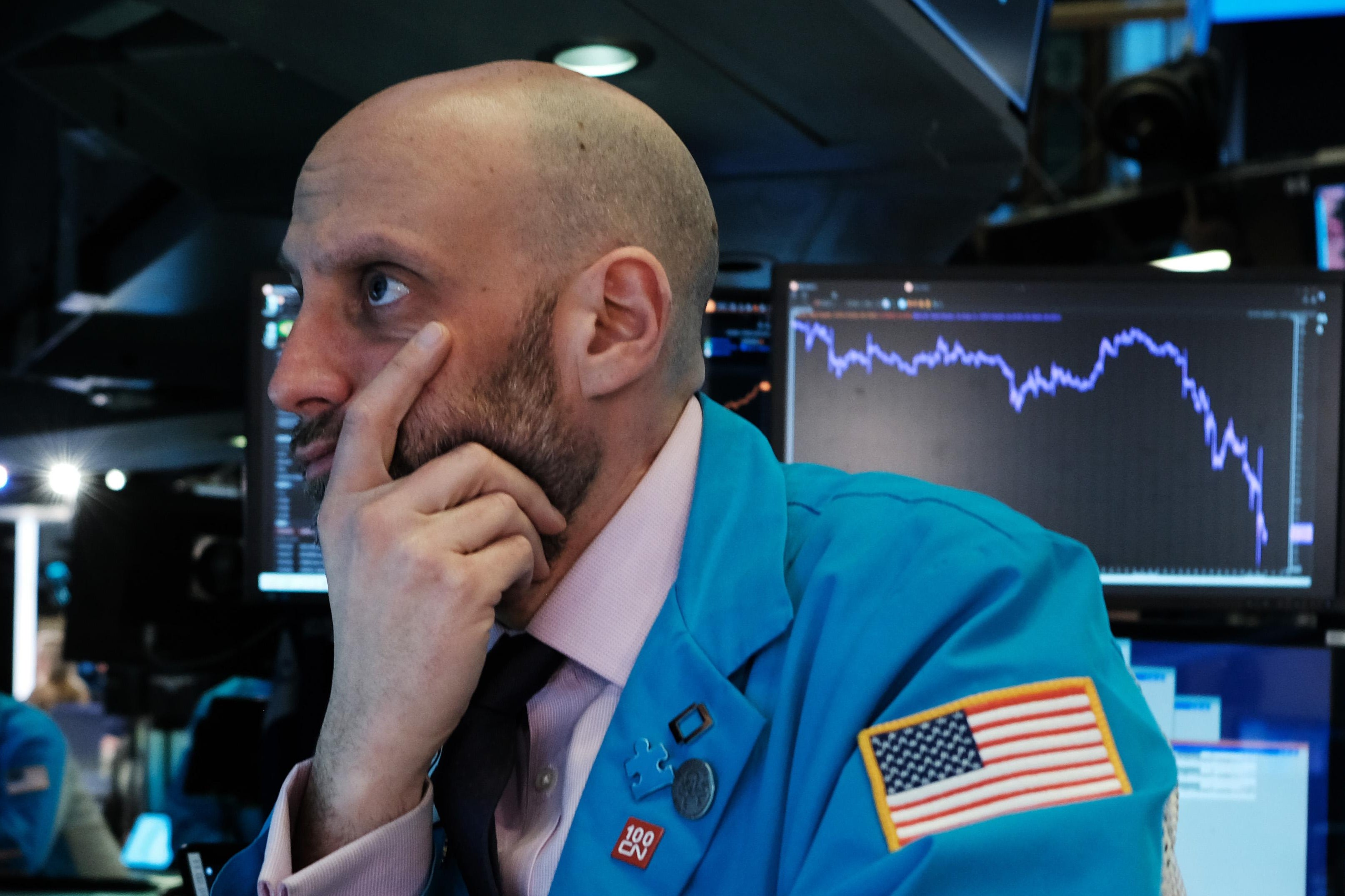 A man in a blue coat clutches his chin