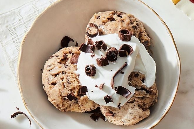 Light brown ice cream topped with whipped cream and chocolate shavings.