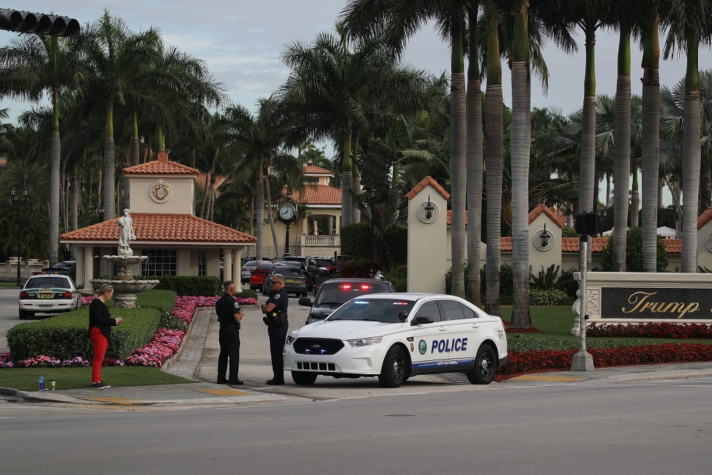 A police car parked in front of a gatehouse entrance to a resort.
