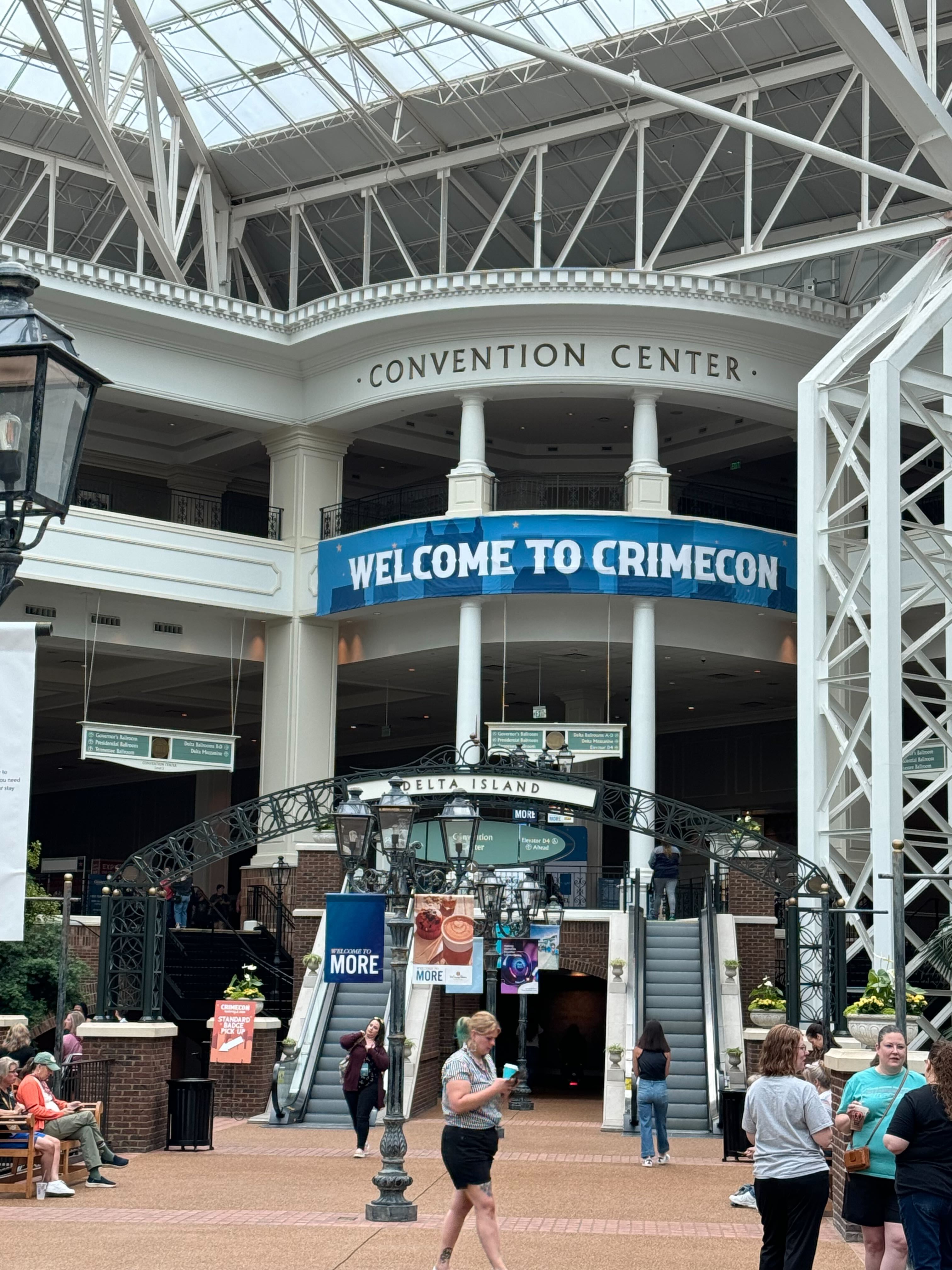 Exterior of a convention center in Gaylord Opryland, with tall white columns and a banner that says "Welcome to CrimeCon."