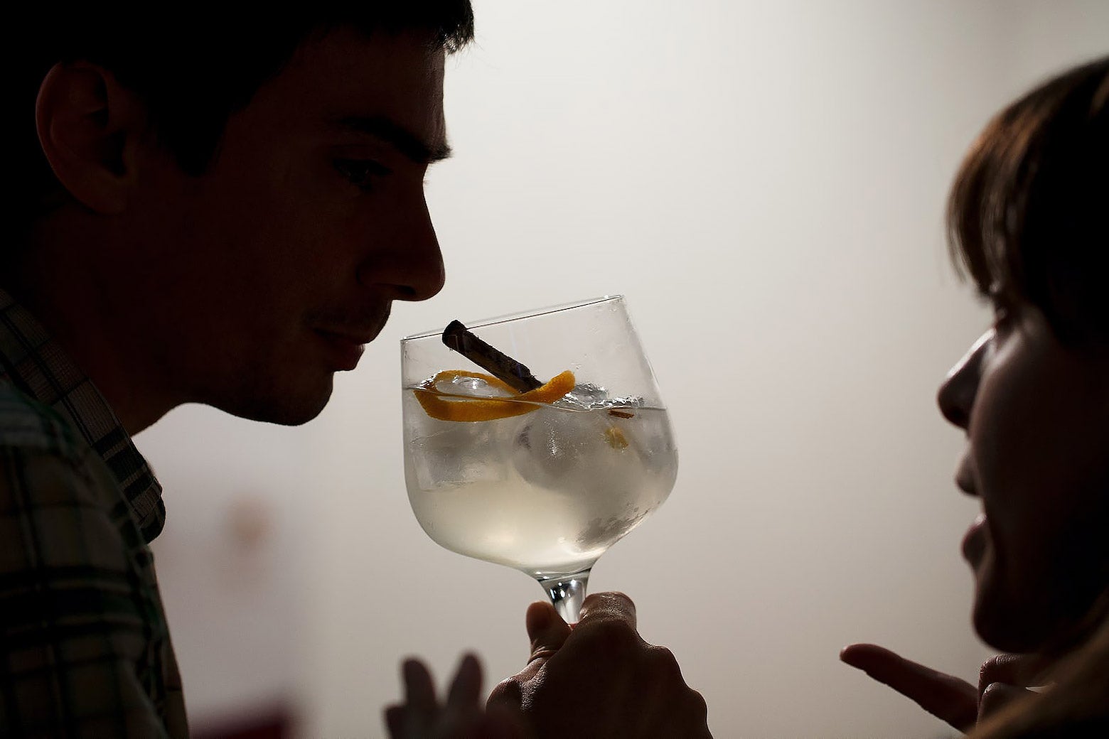 The silhouette of a couple talking while the man holds a clear alcoholic drink.