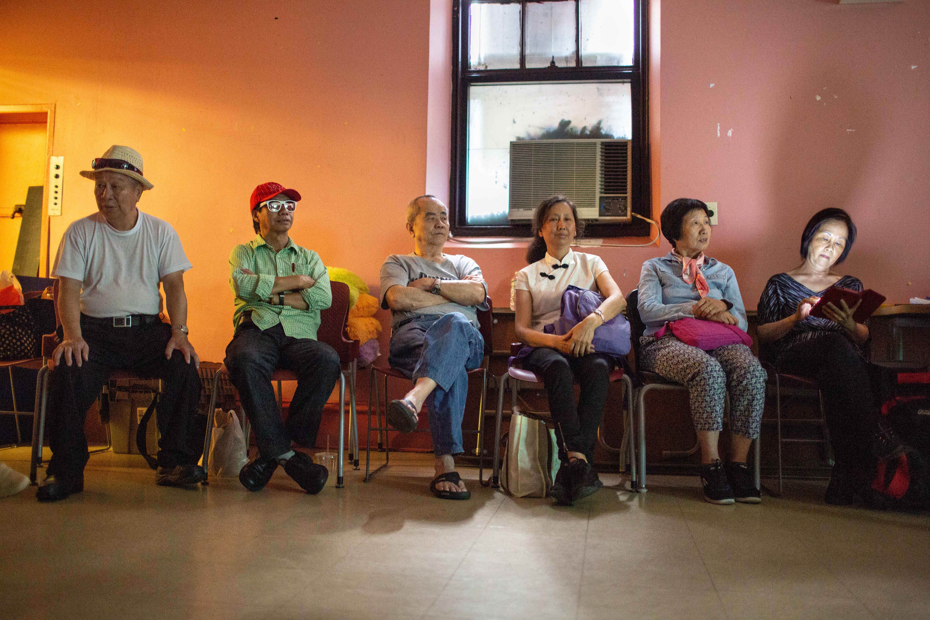 People sitting in a row of chairs waiting their turn at karaoke.