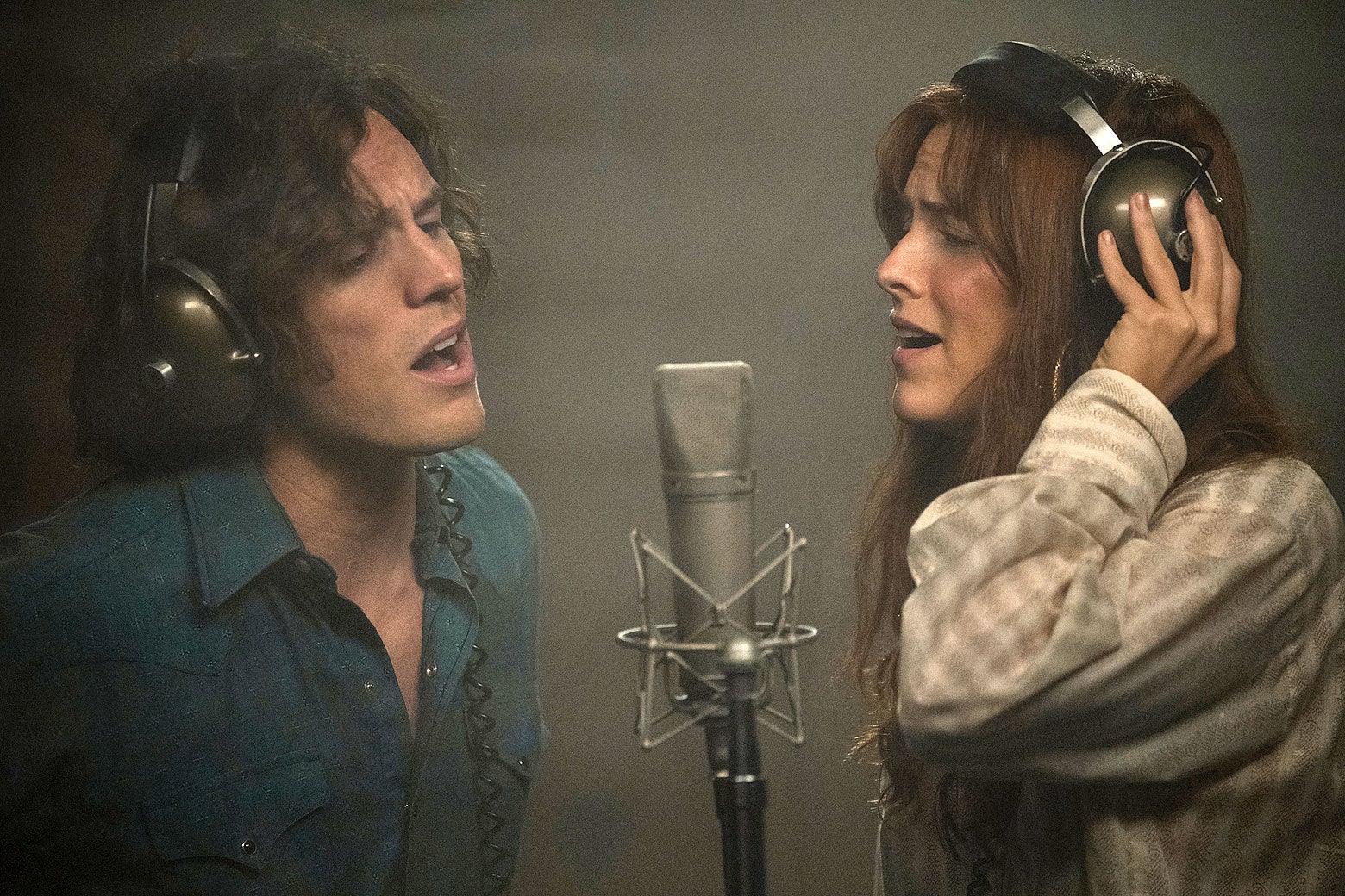 The two sing impassionedly and attractively in ’70s wardrobe into a studio microphone.