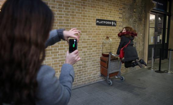 A tourist re-enacts a scene from Harry Potter at King's Cross station 