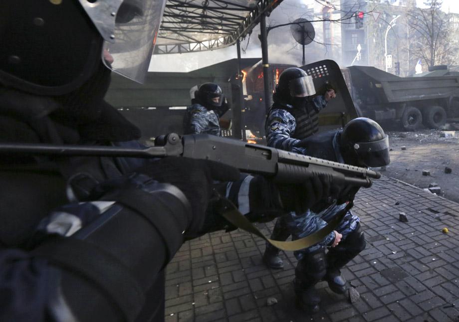 An Interior Ministry officer aims his rifle as others run for cover during clashes with in Kiev on Feb. 18, 2014. UKRAINE/