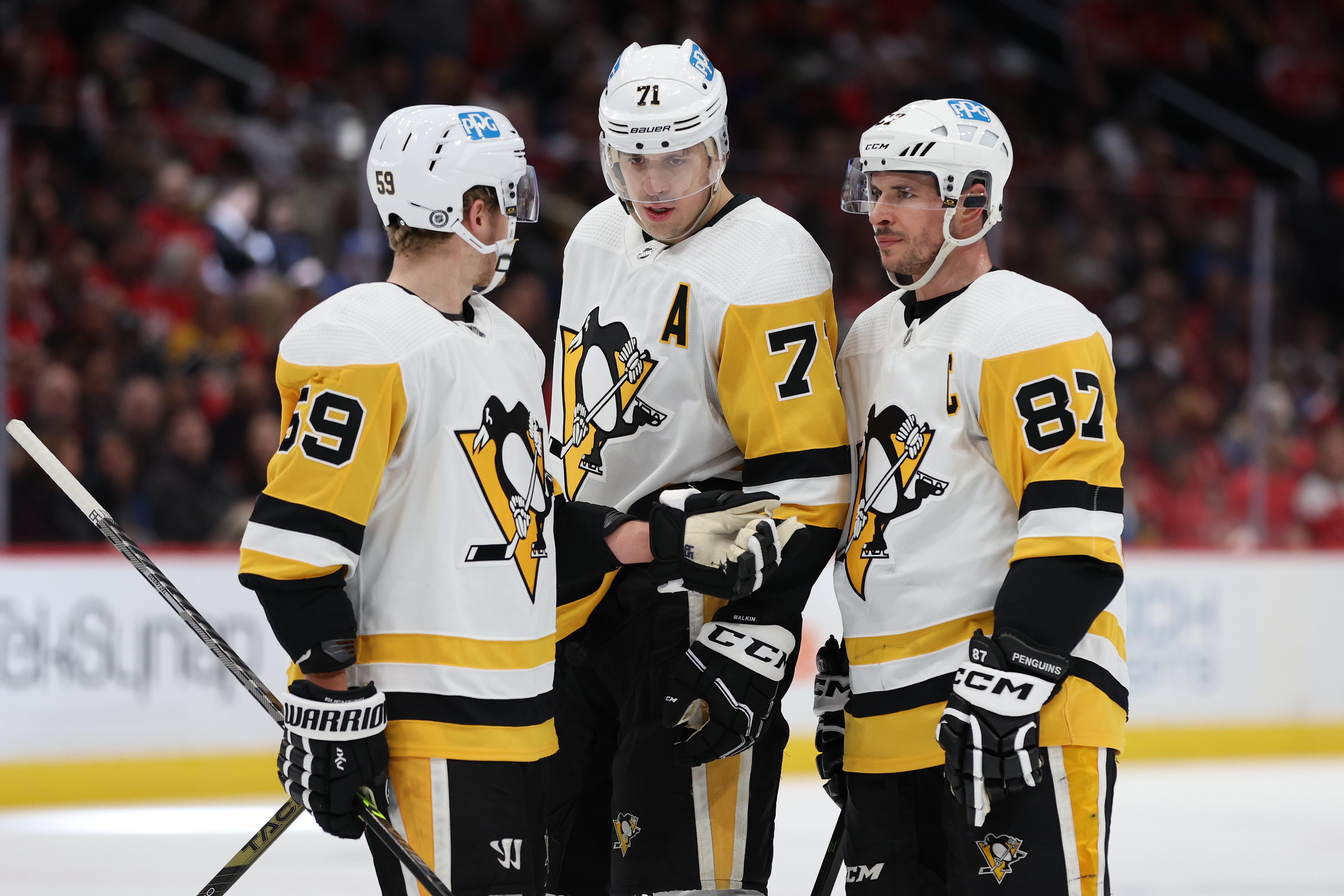 Guentzel, Malkin, and Crosby huddle and talk on the ice.