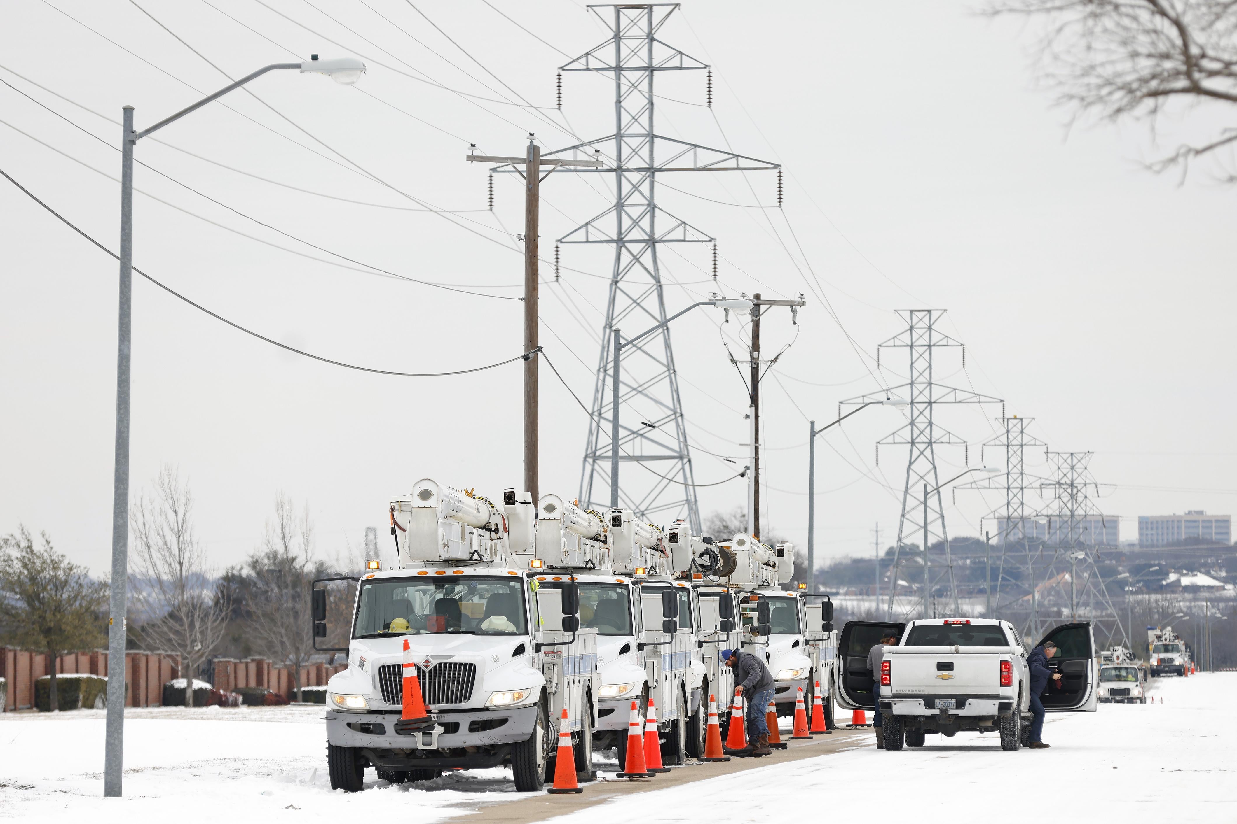 Trucks lined up against an array of power lines, in the midst of widespread snow