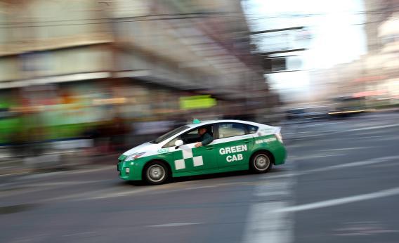 A Toyota Prius hybrid taxi drives across Market Street on in San Francisco