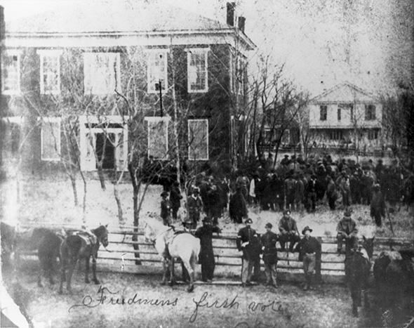 Freedpeople vote for the first time in 1868 at Anderson County Courthouse in Texas. U. S. soldiers stand guard to protect them