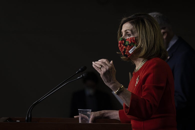 Nancy Pelosi, wearing a face mask, speaks at a microphone.