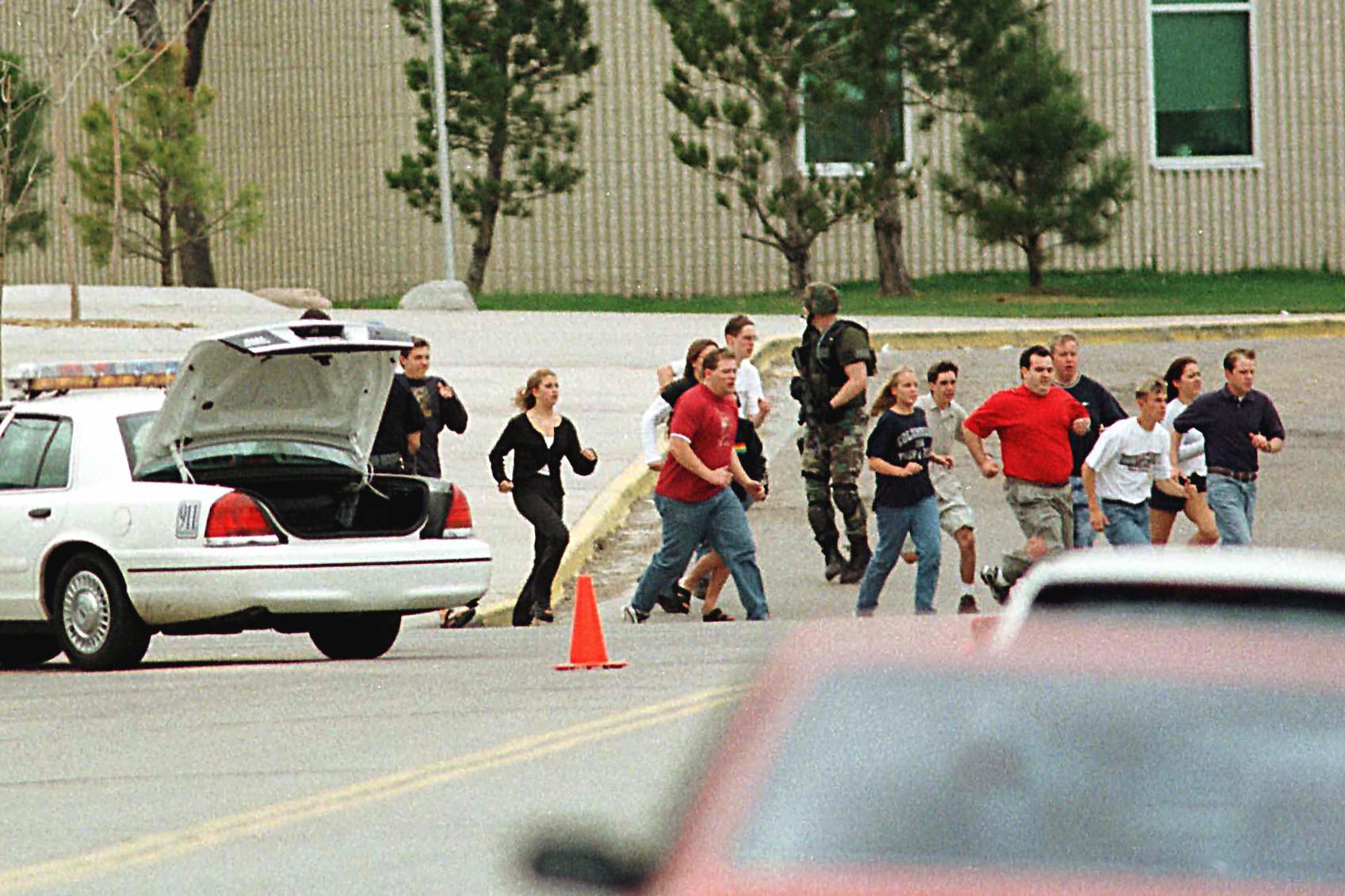 Students run from Columbine High School under cover from police.