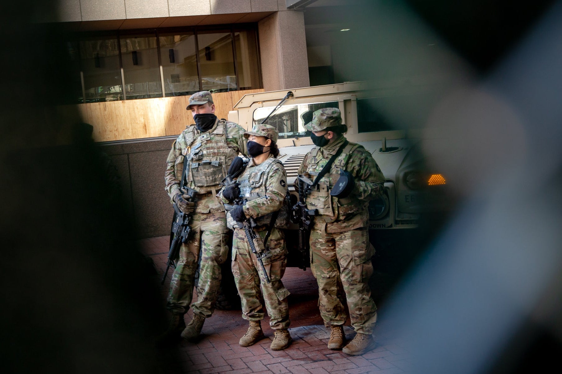 Three National Guard members standing next to an armored vehicle outside the courthouse.